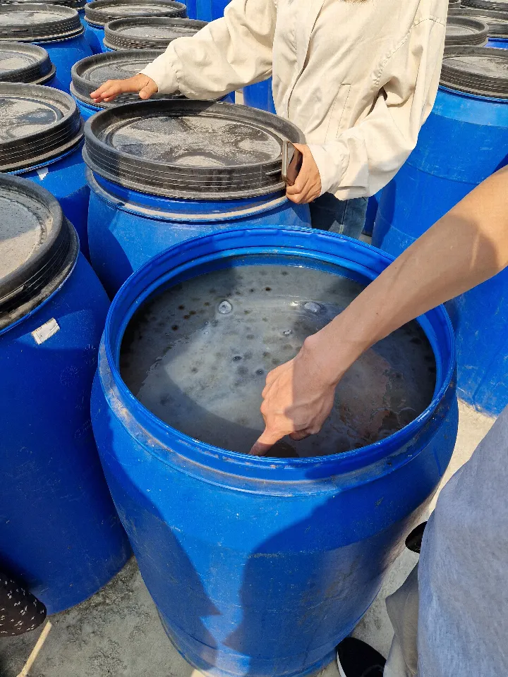 Eine Hand greift in ein blaues, mit Wasser gefülltes Fermentationsfass