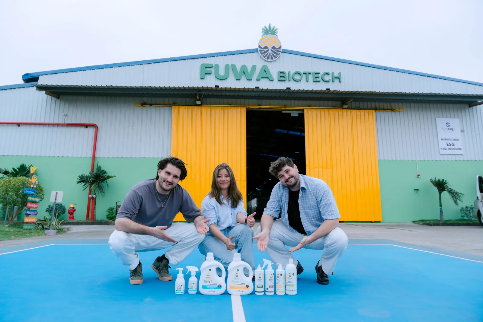 Lars, Huong und Louis vor der FUWA-Biotech-Fabrik in Thanh Hóa, vor ihnen die acht Fruit Warrior Produkte